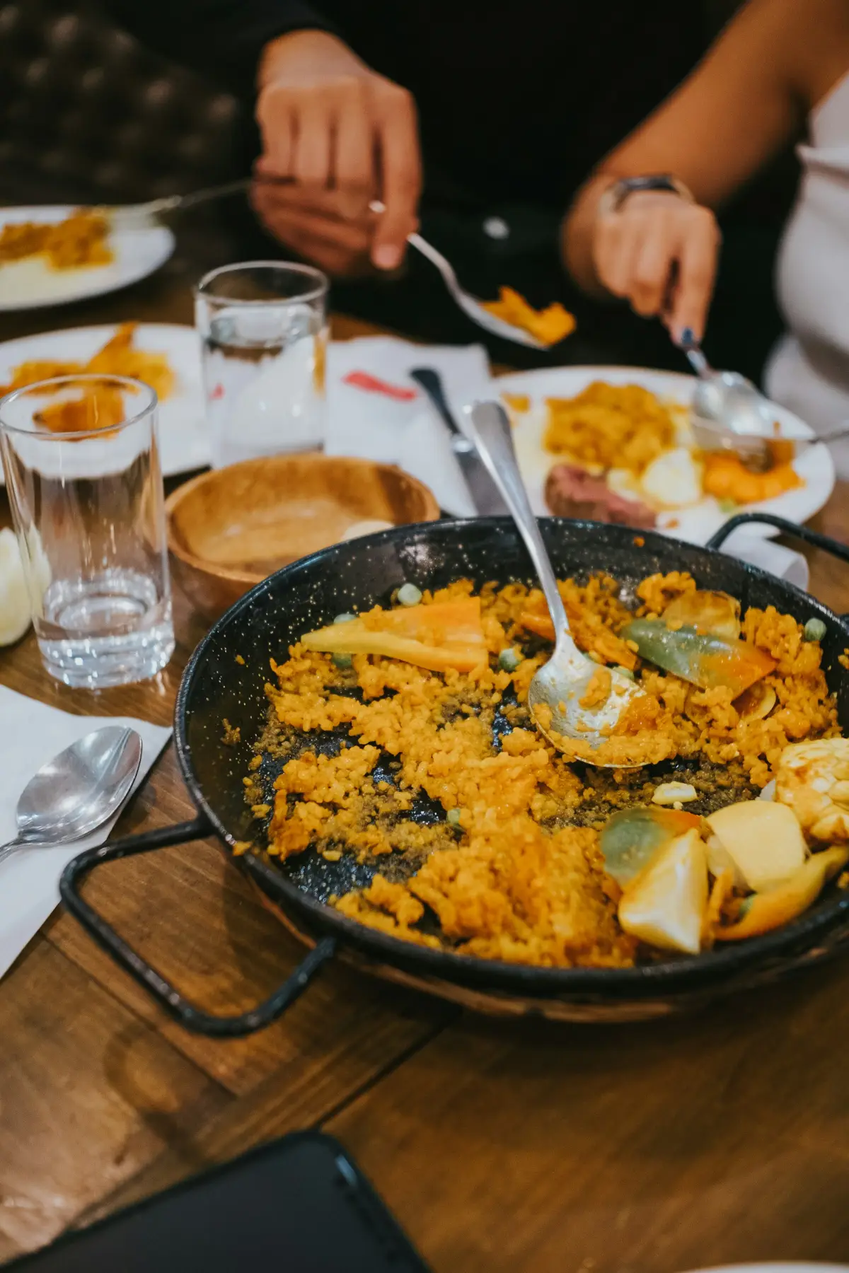 Guests helping themselves to paella from a shared pan